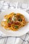 Homemade Bucatini all Amatriciana Pasta in a white plate on a white wooden surface, low angle view. Close-up