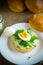 Homemade bun with cheese spread, fresh arugula and boiled egg in a plate