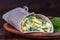 Homemade burrito wraps with boiled eggs, potato, green wild garlic and sour cream for healthy breakfast on plate, closeup