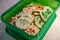 Homemade butter spritz Christmas cookies packed in a green plastic container for easy transport to a party