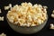 Homemade Buttered Popcorn with Salt in a Bowl on a black background, low angle view. Close-up