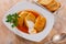 Homemade cabbage rolls in leaves of cabbage at plate with sour cream