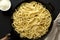 Homemade Cacio E Pepe Pasta with Pecorino Romano and Pepper in a cast-iron pan on a black background, top view. Flat lay, overhead