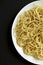 Homemade Cacio E Pepe Pasta with Pecorino Romano and Pepper on a white plate on a black background, top view. Flat lay, overhead,