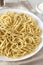 Homemade Cacio E Pepe Pasta with Pecorino Romano and Pepper on a white plate, side view