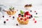 Homemade cake eclairs or profiteroles with custard and berries on light marble background. Holiday dessert, close up