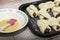 homemade cakes with jam on a baking sheet prepared for baking next to a plate of egg yolk for greasing