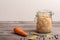 Homemade canned cabbage in jar with carrot and pepper, bay leaves on a wooden table. Rustic style