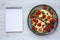 Homemade Caprese Chicken Parmesan with tomato, mozzarella and basil on a Plate, blank notepad, top view. Flat lay, overhead, from