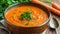 Homemade carrot soup topped with fresh parsley in a rustic bowl