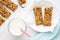 Homemade cereal snacks for healthy eating. Granola bars with milk on white wooden background.