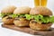 Homemade cheeseburgers on rustic wooden board and glass of cold beer, side view. Close-up