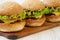 Homemade cheeseburgers on rustic wooden board, side view. Closeup