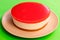 Homemade cheesecake with watermelon jelly on the top, on a bright contrasting green background