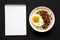 Homemade Cheesy Bacon Savory Oatmeal Bowl, blank notepad on a black background, top view. Overhead, from above, flat lay