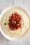 Homemade cheesy dip in a bowl over white wooden surface. From above, flat lay, top view