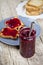 Homemade cherry jam and fresh toasted cereal bread slices plates closeup on rustic wooden table background