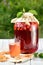 Homemade cherry preserved canned compote in glass with cookies on white wooden table in garden