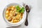 Homemade chicken soup with noodles and potatoes with celery greens on white background.