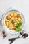 Homemade chicken soup with noodles and potatoes with celery greens on white background. Vertical image