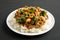 Homemade Chicken Veggie Stir Fry with White Rice on a black background, side view. Close-up