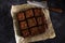 Homemade chocolate brownie dessert with hazelnuts, chocolate glaze and whipped cream on baking paper on a dark background.