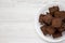 Homemade chocolate brownies on a white plate on a white wooden background, top view. Flat lay, overhead, from above. Copy space