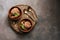 Homemade chocolate ice cream with mint and nuts in bowls on a stump cutting board, dark rustic background. Overhead view, copy