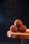 Homemade Chocolate Truffles with Sifting Cocoa on Wooden Board on Dark Background. Copy Space For Your Text