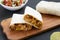 Homemade chorizo breakfast burritos on a rustic wooden board on a black background, low angle view