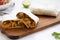 Homemade chorizo breakfast burritos on a rustic wooden board on a white wooden background, side view. Close-up