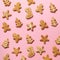 Homemade christmas cookies on pink background. Square crop. Pattern of gingerbread men, snowflake, star, fir-tree, boot shapes.