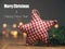 Homemade cloth star with fir branches on a wooden table in front of a Christmas lights bokeh