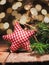 Homemade cloth star with fir branches on a wooden table in front of a Christmas tree bokeh