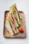 Homemade club sandwich made with turkey, bacon, ham, tomato, on white background