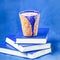 Homemade coffee latte with cinnamon and three books on blue background. Shades of blue, copy space