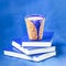 Homemade coffee latte with cinnamon and three books on blue background. Shades of blue, copy space