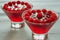 Homemade cold raspberry jelly with fresh cherries in two glasses. Freshness healthy summer dessert on the gray background