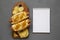 Homemade colombian hot dogs with pineapple sauce, chips and mayo ketchup on a rustic wooden board, blank notepad on a gray