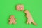 Homemade cookies in shapes of dinosaur and man with inscription â€˜Stay safeâ€™ on green background, top view.