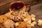 Homemade cookies with sunflower seeds and raisins, pieces of brown cane sugar and an earthenware mug of tea on a wooden table.