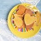Homemade cookies on a yellow plate with knitted lace tablecloth on a kitchen table