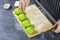 Homemade cooking concept. Hand of chef man sprinkling sesame seeds on green dough vegetarian on wooden board with whole wheat on