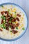 Homemade Corn Chowder with Bacon in a Bowl on a white wooden background, top view. Flat lay, overhead, from above