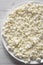 Homemade cottage cheese on a white plate, top view. Flat lay, overhead, from above. Close-up