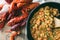 Homemade crawfish etouffee in a cast iron pan. Shown with whole boiled crawfish on a wood background.