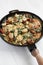 Homemade Creamy Tuscan Chicken in a cast-iron pan on a white wooden surface, low angle view