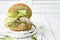 Homemade crispy spring fish burger with spicy chilli mayo on white rustic wooden board over light background. Copy space.