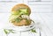 Homemade crispy spring fish burger with spicy chilli mayo on white rustic wooden board over light background. Copy space.