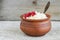 Homemade crumbly farmer\\\'s cheese in a clay pot. Selective focus. Wooden background.